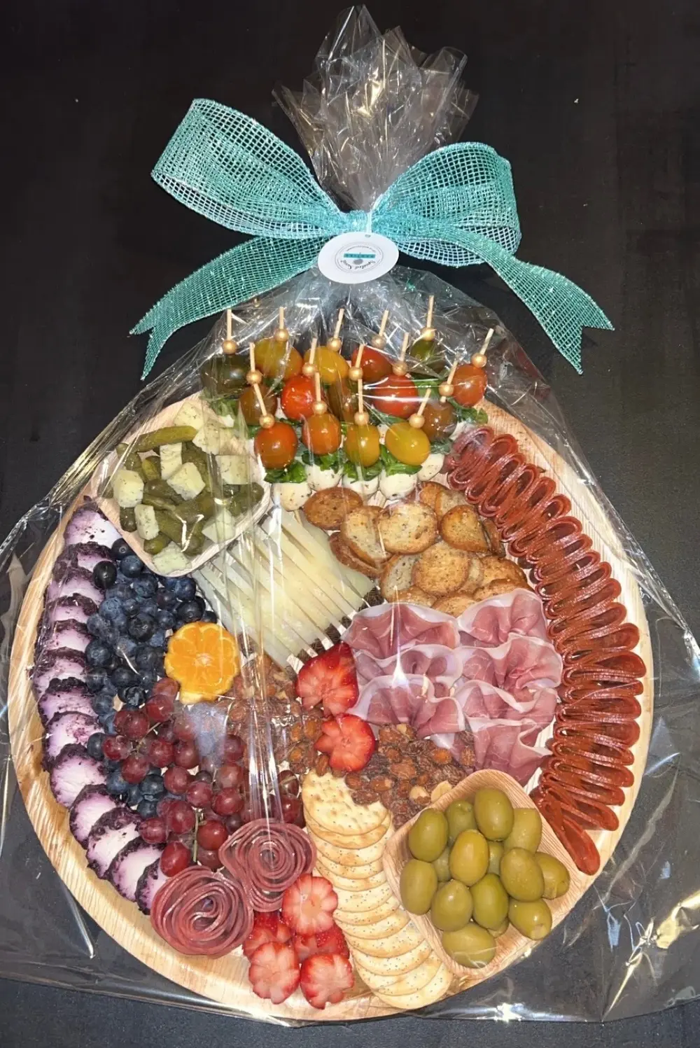 Charcuterie board to go wrapped in cellophane tied with ribbon and spoiled sweet branding